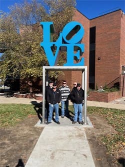 A picture of the "LOVE" sculpture and the men who installed it at the Ulrich Museum.