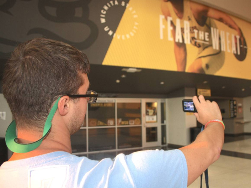 A student takes a photo in Charles Koch Arena for PhotoVoice