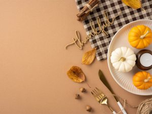 A plate with small pumpkins on it surrounded by fall items and the word "Thankful" made of wood