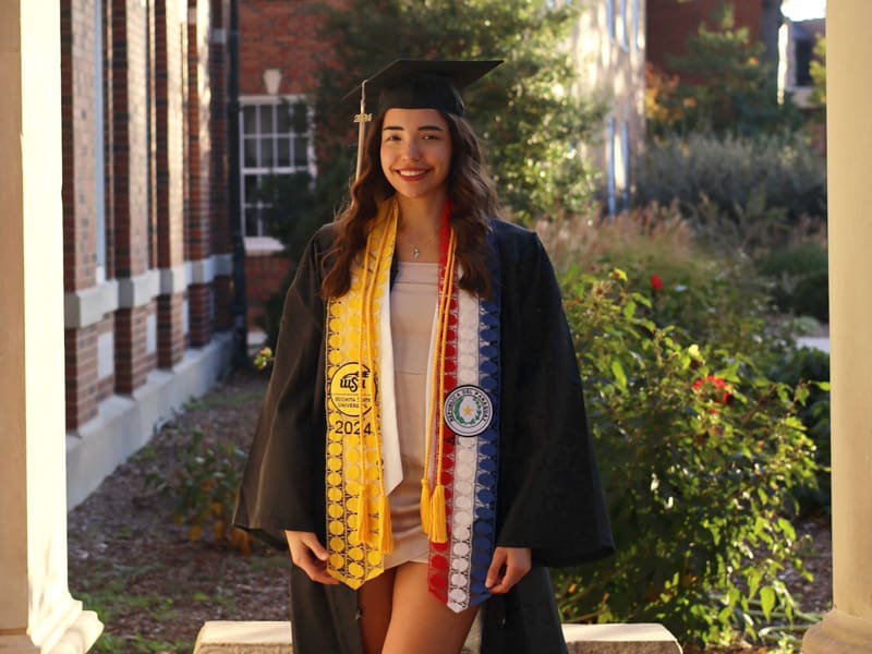 Aracely Martinez in her graduation regalia on Wichita State's campus