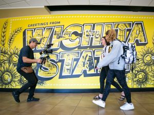 Students in the middle of filming in front of the Wichita State mural in the RSC.