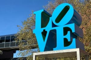 A close-up image of Robert Indiana's sculpture LOVE, a large rendering of the word "Love" in blue and green metal.