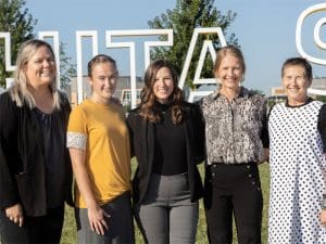 The pediatric physical therapy team at Wichita State pose in front of the Wichita State sign.