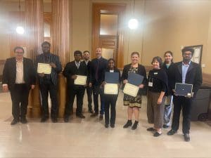 Dr. Enrique Navarro and Dr. Coleen Pugh standing with students from WSU at the awards ceremony of the Capitol Graduate Research Summit.