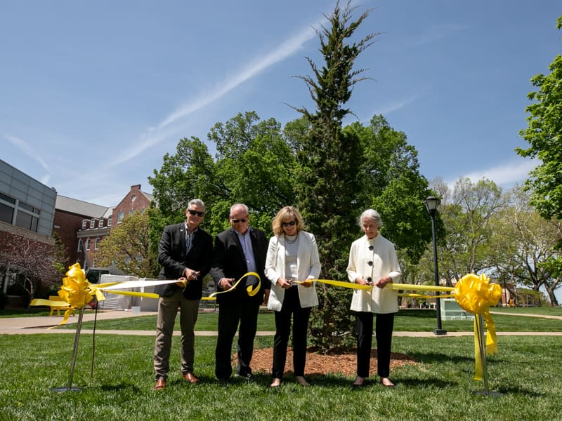 President Rick Muma, Beverly Rhatigan, Becky Linot and Joe Linot cut a ribbon to officially dedicate a tree to Dr. James Rhatigan