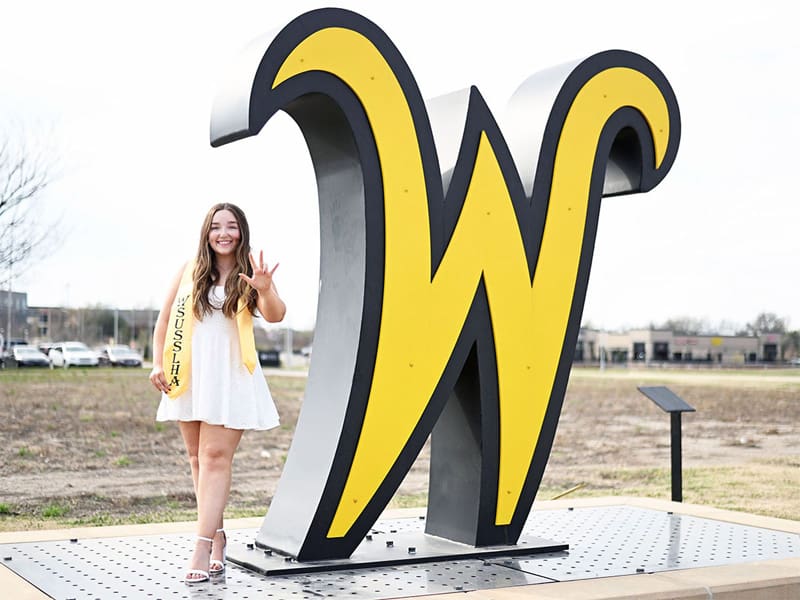 Bryonna Hawk posing next to the flying W sign on campus