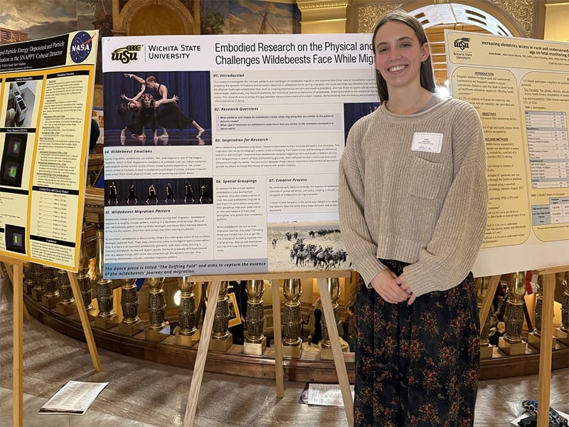 Lille Nightingale poses with her poster presentation at the Undergraduate Research Day at the Capitol