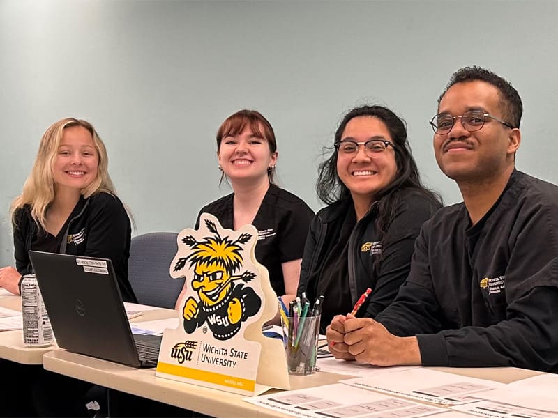 Members of team two pose at a table with their work.
