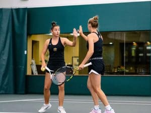 Women's tennis players celebrate after a successful set