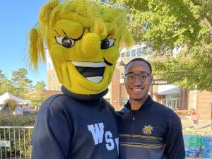 Tyler Winn poses with WuShock outside of Shocker Hall