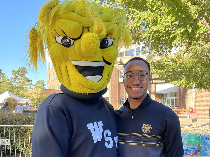 Tyler Winn poses with WuShock outside of Shocker Hall