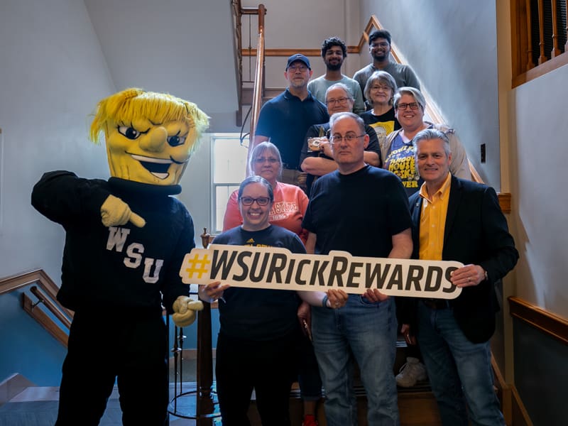 President Rick Muma and WuShock pose with the Post Office staff in Morrison Hall.