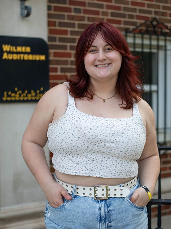 Photo of Alexandra Enmark standing on the steps outside of Wilner Auditorium