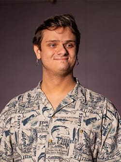 Professional photo of Luke Samuelson. Luke has short brown hair and is looking right of the camera. He's wearing a button up fishing shirt.