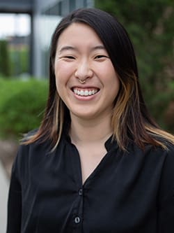 Headshot of Janis Hwang with greenery and a building blurred in the background