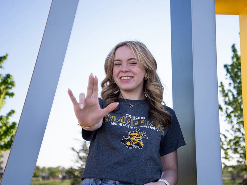 Karaline Scott gives a WSU Shocker hand sign to the camera