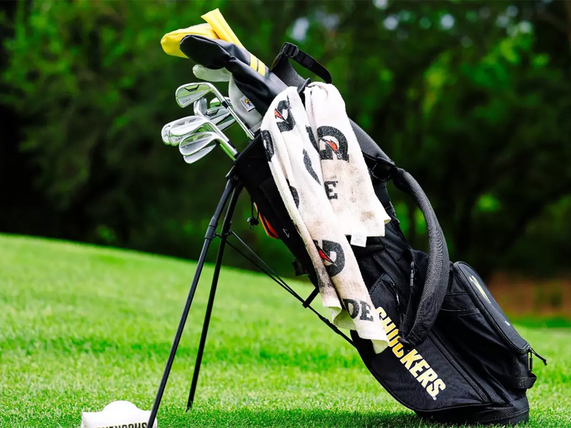 A Shocker-branded golf bag is propped up on the pitch filled with different golf clubs and different towels