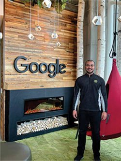 Lucas Garces standing in a room with Google's logo on a fireplace wall.