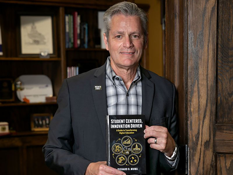 President Richard Muma poses with his book "Student Centered, Innovation Driven."