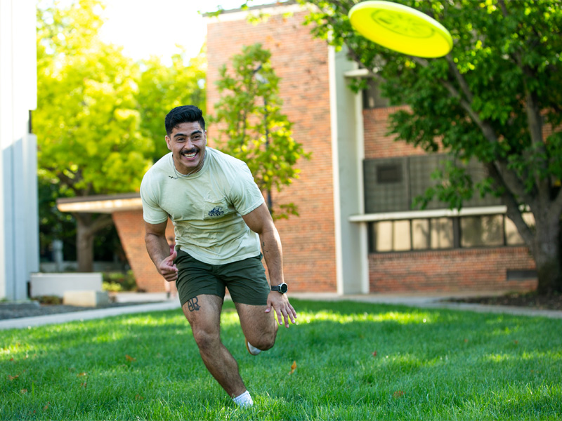 A student playing frisbee on campus