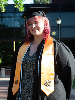 Niki Noland standing in their cap and gown.