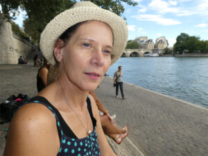 A woman in a hat is relaxing by a river.