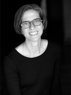 Black and white headshot of a white woman wearing glasses, a dark sweater, and with a bob haircut