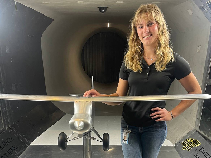 Sarah Varner with a model airplane at the Walter H. Beech Wind Tunnel
