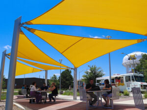 Students enjoy food from the Food Truck Plaza at the covered seating area with the WSU water tower in the background