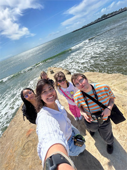 Five students standing on a cliff overlooking the sea.