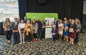 A group of people holding plaques and standing in front of a large banner that reads "Partners in Peace"