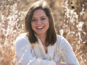 A smiling woman sits in a field