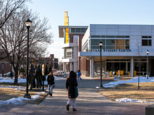 Students walk around in front of the Rhatigan Student Center with a little bit of snow piled up