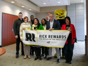 Rick Muma and WuShock pose with a banner that says Rick Rewards with the SEM Leadership Committee