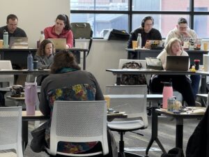Faculty sit working on laptops at their computers during the January 2026 FARE Research & Writing Sprint.