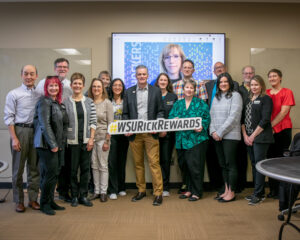 President Rick Muma holds up a sign saying Rick Rewards with members of the Department of Communication Sciences and Disorders.