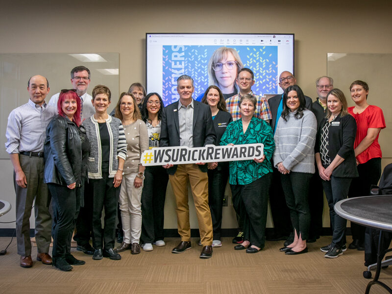 President Rick Muma holds up a sign saying Rick Rewards with members of the Department of Communication Sciences and Disorders.