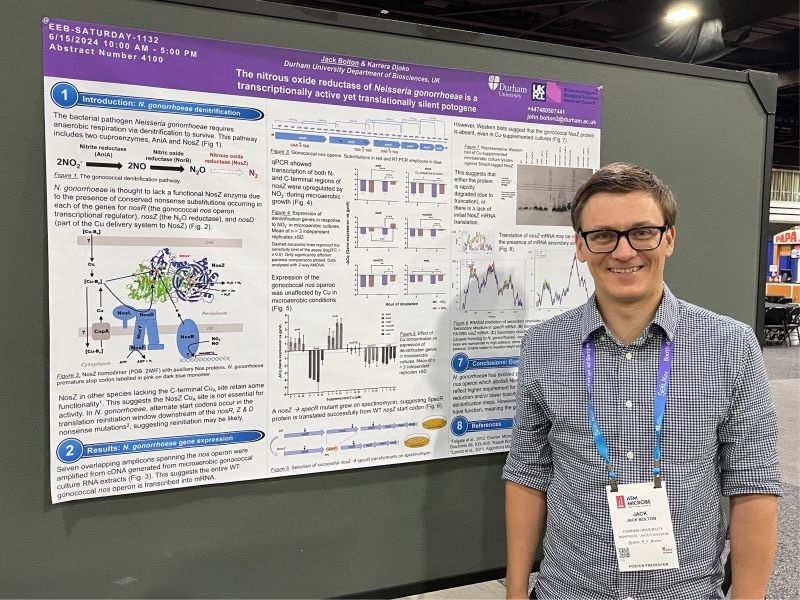 Photograph of Dr. Jack Bolton standing next to a scientific poster.