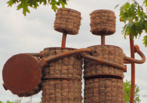 The sculpture, Shockers by Tom Otterness, is a Corten steel frame filled with hay that forms the figures of two friends.