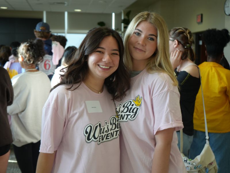 Two student volunteers, standing and posing shoulder to shoulder.