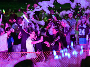 Students take part in the foam party at night with a purple light shining across them