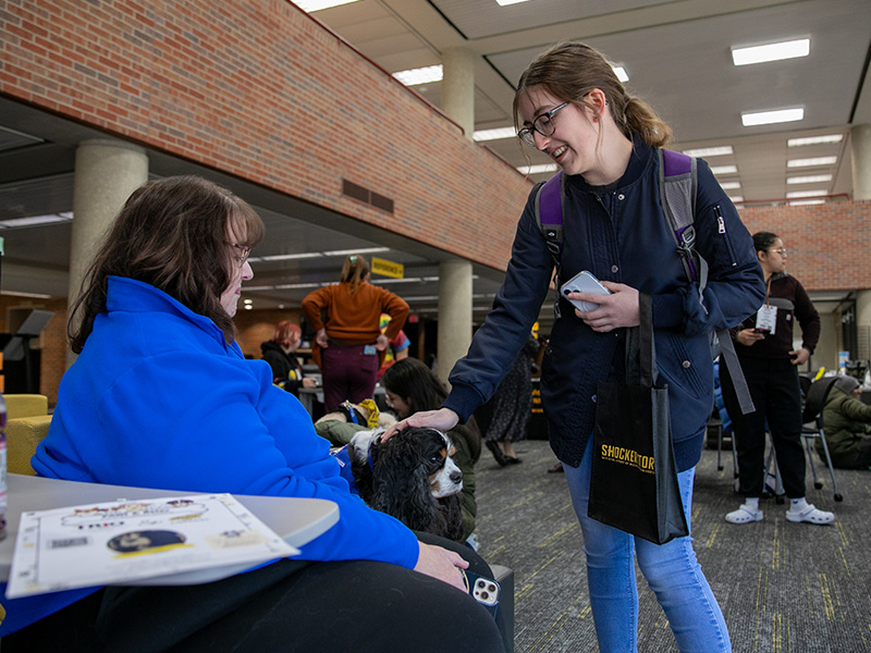 A students pets a dog at an event in the Ablah Library