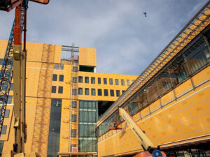 Construction vehicles work on the orange backup wall panels on the Wichita Biomedical Campus exterior