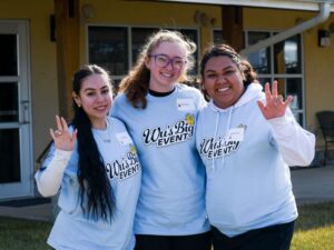 Three student volunteers standing and posing arm in arm.