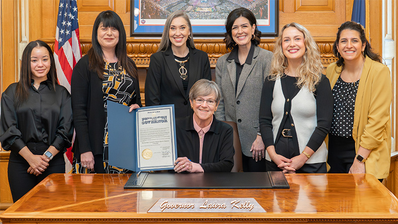 Gov. Laura Kelly holds up the signed proclamation for the Barton School's centennial year with representatives from the Barton School