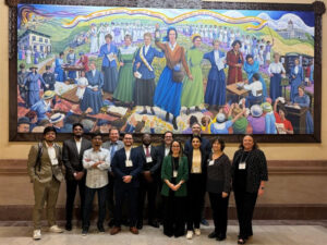 Group picture of WSU students who presented their research in Topeka. they are posing in front of a huge painting at the Kansas Capitol.