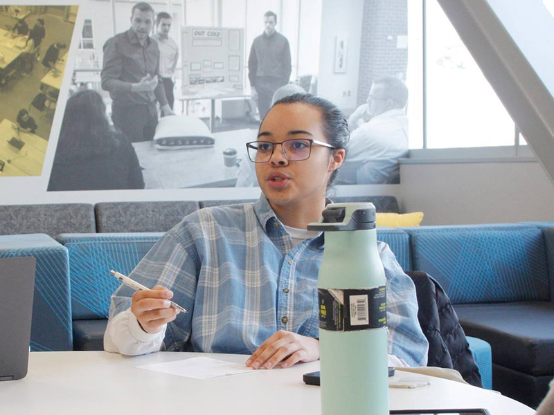 A student in Shocker Design Experience takes notes as her team discusses their project