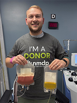 Joshua Geisler wears an I'm a Donor T-shirt while holding up two IV bags full of liquid