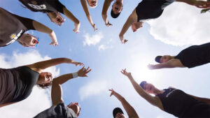 The women's tennis team huddles in a circle and gives the Shocker hand sign.