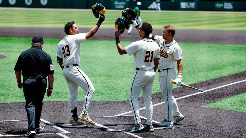 Members of the baseball team bump helmets in celebration at home base